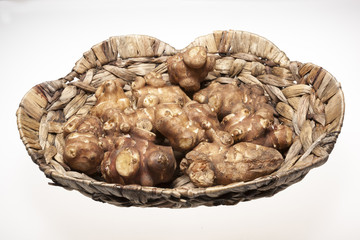 Jersalem Artichoke (Helianthus tuberosus) vegetable in wicker basket isolated on a white studio background.
