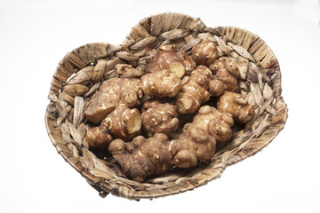 Obraz premium Jersalem Artichoke (Helianthus tuberosus) vegetable in wicker basket isolated on a white studio background.