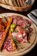 meat sliced proshto, salami, olives and pepper paprika on a wooden plate