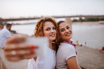 Close-up image of two female friends making selfie outdoors.