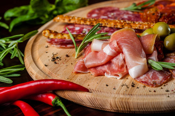 meat sliced proshto, salami, olives and pepper paprika on a wooden plate