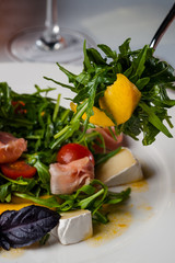 dish in the restaurant fresh salad with basil, prosciutto, tomato and mozzarella