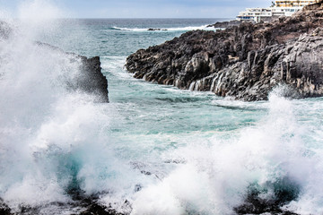 Obraz premium Seascape with black volcanic rocks, waves and splashes