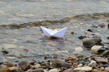 Papierschiffchen treibt in seichtem Wasser