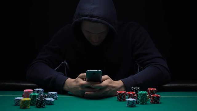 Anonymous male playing online game on smartphone app, illegal business, addict
