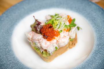 A delicious homemade shrimp sandwich with lettuce, tomato, tartar sauce and red caviar.