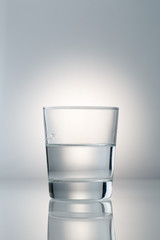 glass with water on gradient light gray background