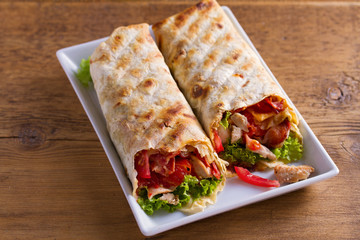 Chicken caesar salad wraps with bacon, tomatoes, lettuce and cheese. Tortilla, burritos, sandwiches twisted rolls
