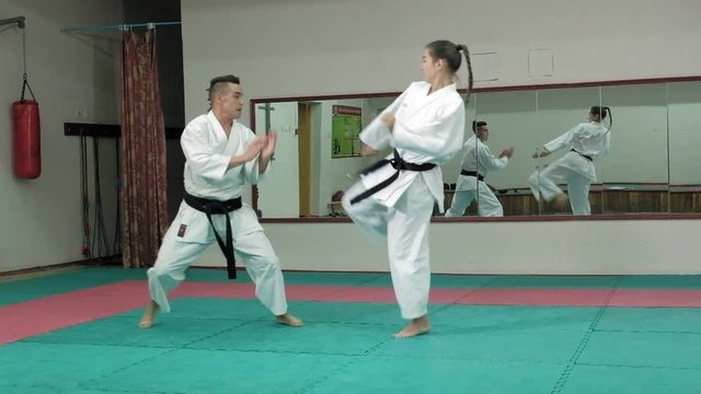 A young man with a muscular body and a woman practicing martial arts Goju-Ryu Karate-Do super slow motion
