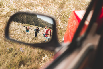 car mirror reflection of group of young people running by field