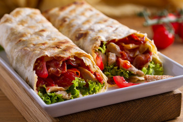 Chicken caesar salad wraps with bacon, tomatoes, lettuce and cheese. Tortilla, burritos, sandwiches...