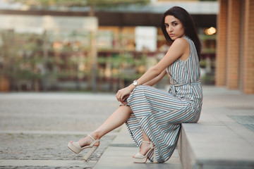 Woman fashion model posing sitting in city