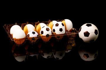 Footballs among the white eggs in the egg tray. Soccer bolls in the egg tray. So there appear soccer balls