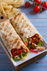 Chicken caesar salad wraps with bacon, tomatoes, lettuce and cheese. Tortilla, burritos, sandwiches twisted rolls