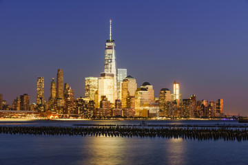 Lower Manhattan skycrapers illuminated at twilight with the Hudson River. Manhattan, New York City