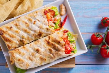 Chicken caesar salad wraps with bacon, tomatoes, lettuce and cheese. Tortilla, burritos, sandwiches twisted rolls. View from above, top