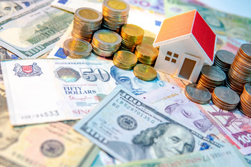 Real estate or property investment. Home mortgage loan rate. Saving money for retirement concept. Coin stack on various of international banknotes with house model on table. Business growth concept.