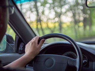 Man driving a car, close-up photo. The driver is holding the steering wheel.