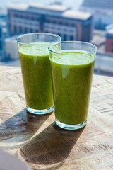 Fresh green healthy smoothie in sunlight on wooden background. 