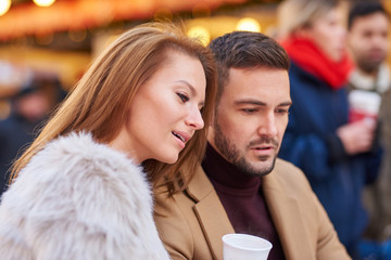 Fototapeta premium Portrait of a beautiful young couple drinking mulled wine in a christmas market.