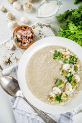 Mushroom champignon cream soup in a bowl with parsley, white marble background copy space