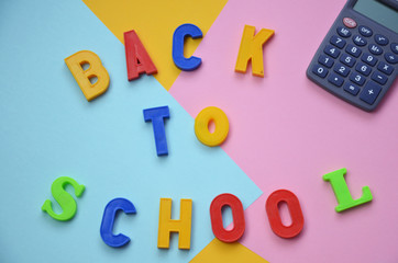 School office supplies with copy space. Back to school text concept. inscription flattering back to school on a colorful bright abstract  Top view.