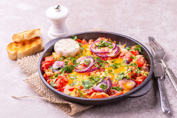 Shakshuka with toasts. Fried eggs with tomatoes, vegetables and herbs