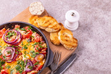 Shakshuka with toasts. Fried eggs with tomatoes, vegetables and herbs