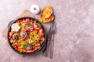 Shakshuka with toasts. Fried eggs with tomatoes, vegetables and herbs