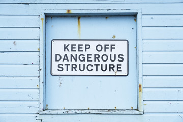 Keep off dangerous structure sign on duck egg coloured wooden wall