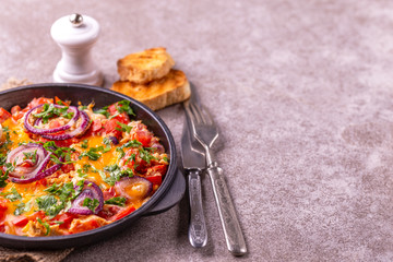 Shakshuka with toasts. Fried eggs with tomatoes, vegetables and herbs