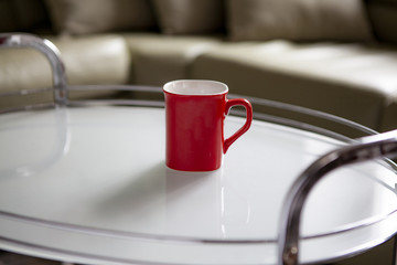The red cup is on the coffee table.