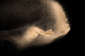 Dry river sand with stone explosion. Yellow colored sand splash agianst dark background.