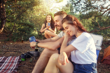 Party, camping of men and women group at forest. They relaxing against green grass. The vacation, summer, adventure, lifestyle, picnic concept