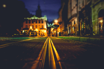 Illuminated street of old european town at night. Tilt-shift effect