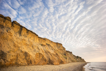 especial shape of clouds above golden sea coast in summer morning