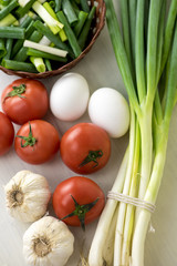 Assortment of fresh vegetables close up-green onions, garlic, beef tomatoes, white eggs