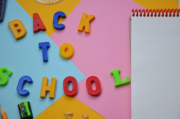 School office supplies with copy space. Back to school text concept. inscription flattering back to school on a colorful bright abstract  Top view.