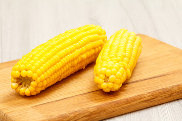 Cutting board with boiled corn on table