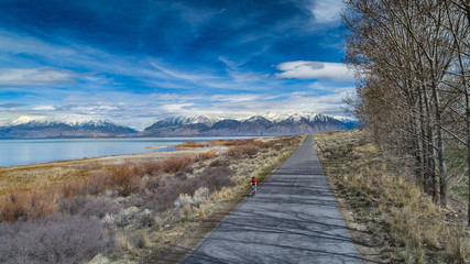 Aerial view of female cyclist riding next to lake in the mountains