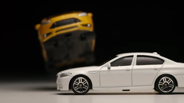 SLOW MOTION: Yellow toy car jumps across a white toy car