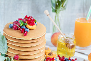 Fresh delicious pancakes with summer berries on light background.