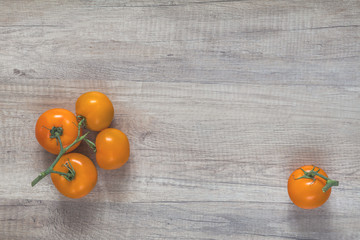 Fototapeta na wymiar Branch yellow tomatoes on light wooden surface.