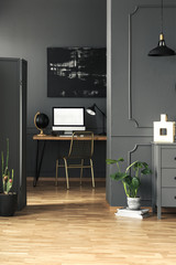 Open space living room interior with molding on the wall in real photo of home office corner with gold chair and mockup computer
