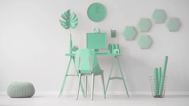 Video of a mint green office interior with hexagon wall decoration next to a desk with computer and monstera leaf. Cinemagraph of oversize dice being thrown in the room.