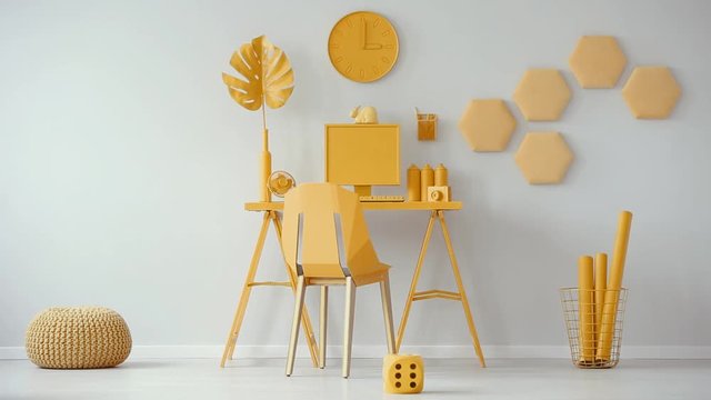 Yellow chair at a desk with computer, monstera leaf, spray cans and camera. Video cinemagraph