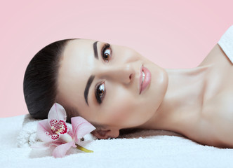 Portrait of a beautiful woman in a spa salon with an orchid. Professional skin care.