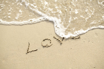 Love written on the beach by the sea in the morning