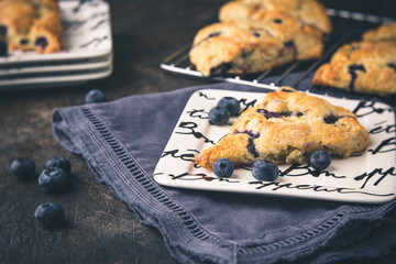 Homemade Blueberry Scones on a White Bon Appetite Dish; More Scones in Background on Wire Rack;...