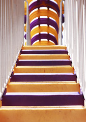 Colorful violet and yellow plastic stairs with white metal railing going up